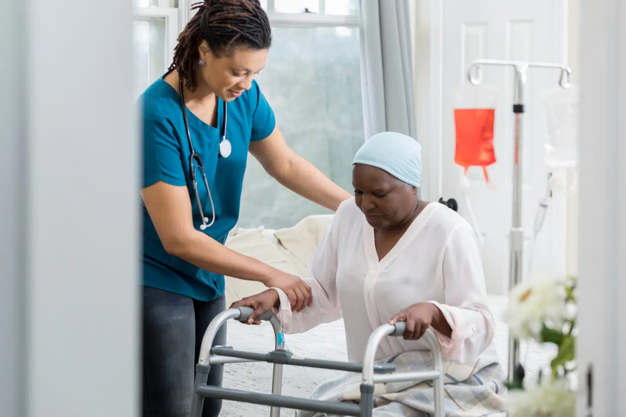 Health aid helping woman out of bed