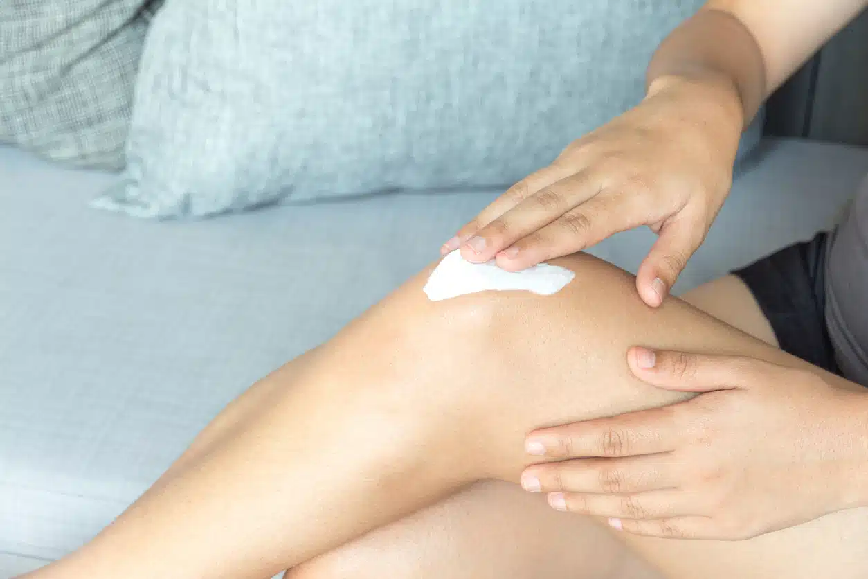 Woman putting lotion on her legs and knees