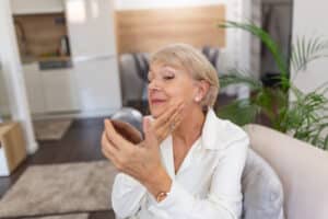 Older woman looking at her face in a hand mirror