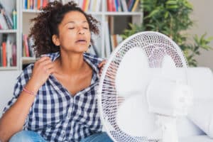 Woman having a hot flash, cooling off with a fan