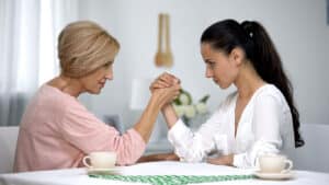 Mother and daughter-in-law looking on each other during arm wrestling battle
