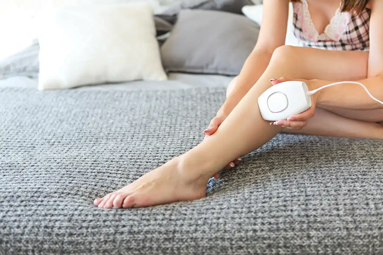Woman doing laser hair removal at home on her bed