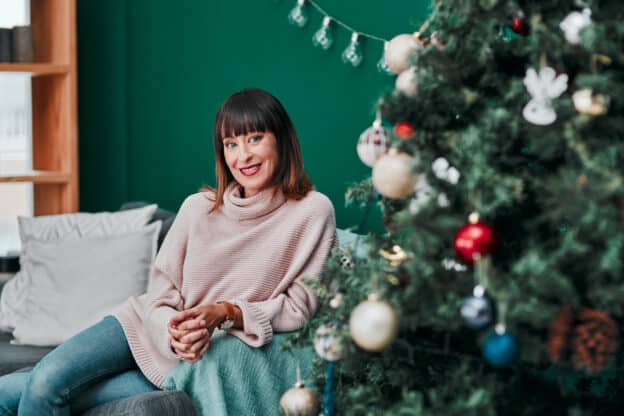 Surviving the holidays single; woman sitting by a Christmas Tree