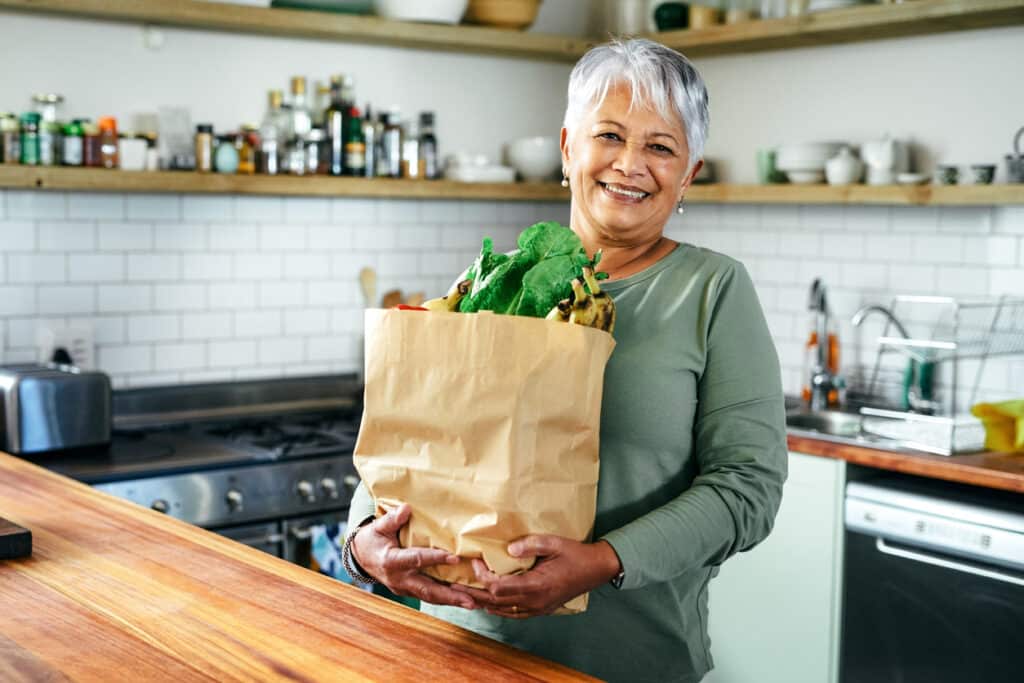 Woman with grocery bag of healthy foods that prevent breast cancer