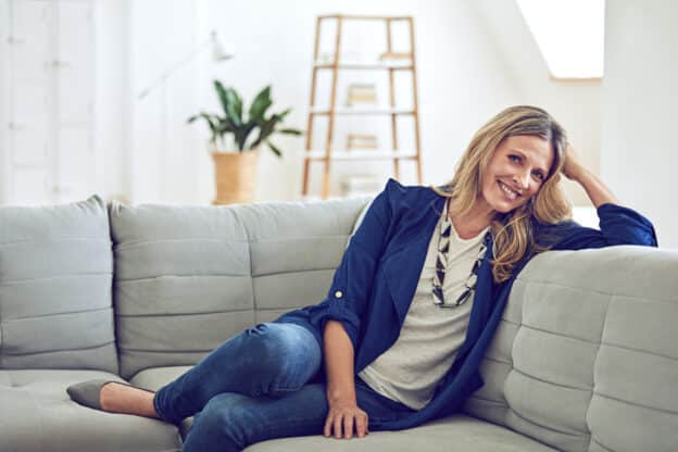 Woman wearing a blazer on the couch with jeans