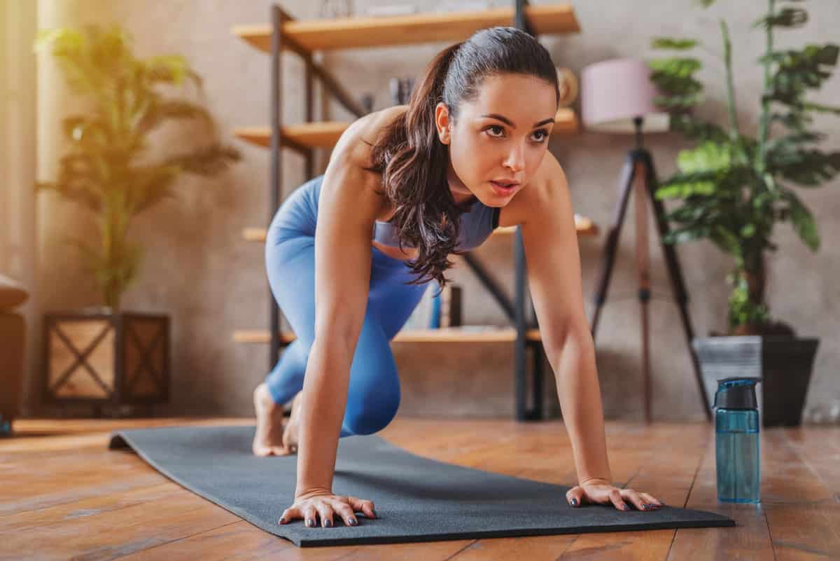 Woman doing mountain climbers exercise inside her home
