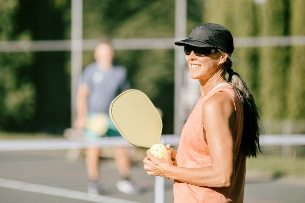 woman playing pickleball with a hat