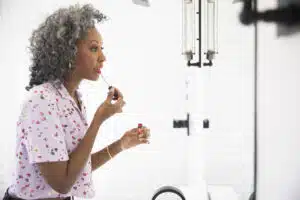 Best lip stains for women over 50; woman applying lip gloss; Makeup for older women