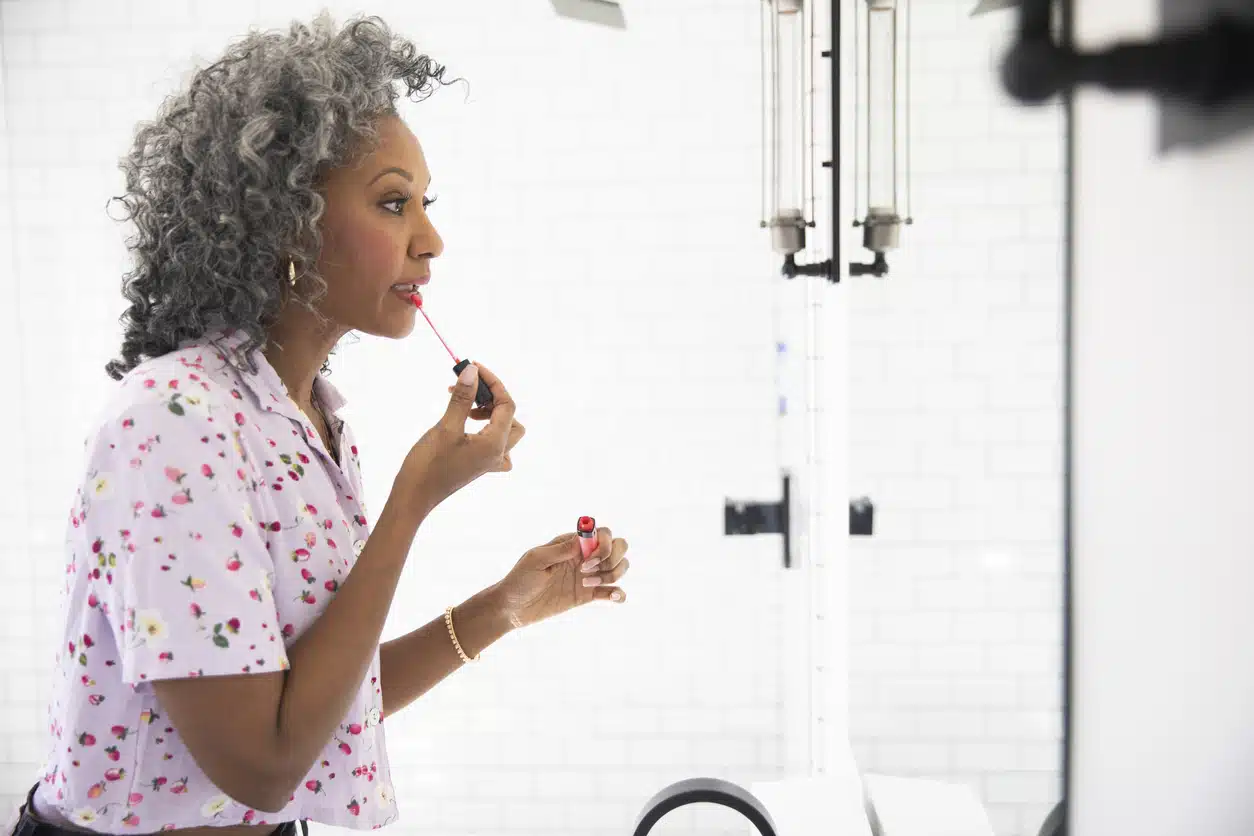 Best lip stains for women over 50; woman applying lip gloss; Makeup for older women