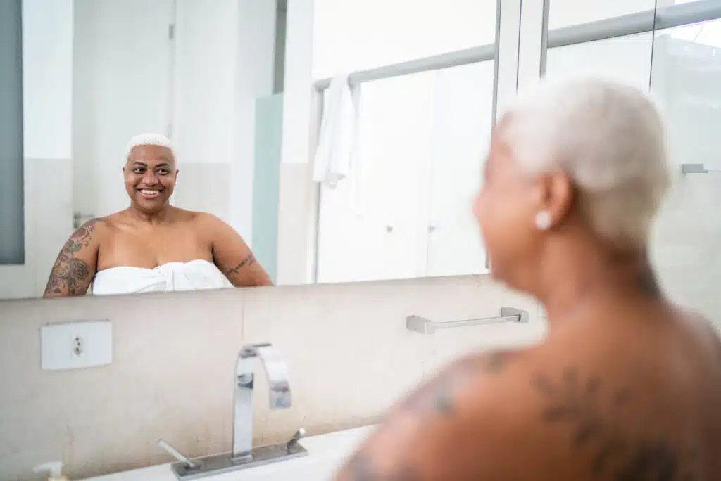 Mature woman looking in the mirror at home