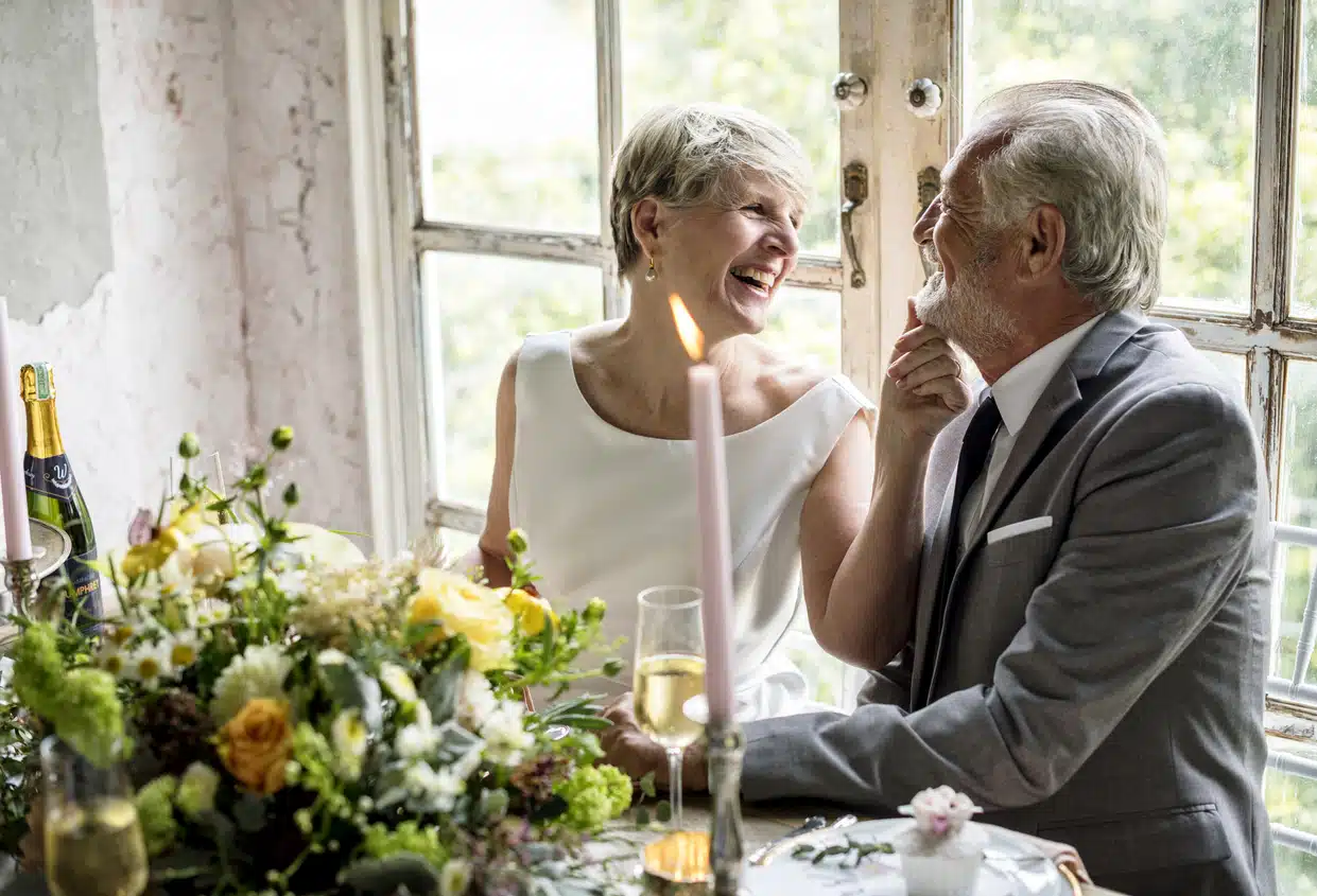 Senior bride and groom sitting laughing together