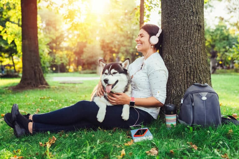 Audible UK - Woman listening to an audio book outside with her dog