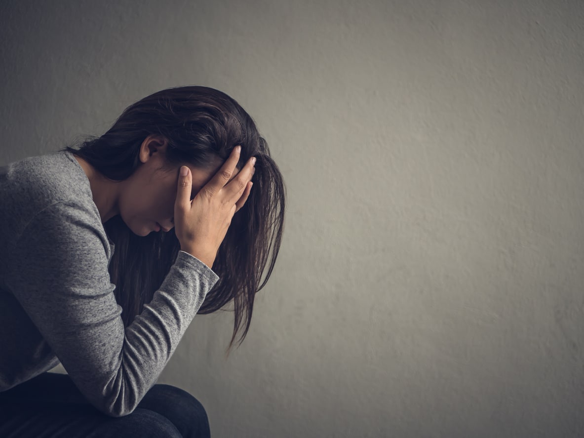 Depressed woman with her head in her hands side view