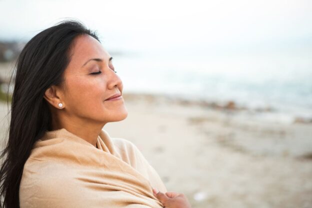Woman taking a deep breath on the beach
