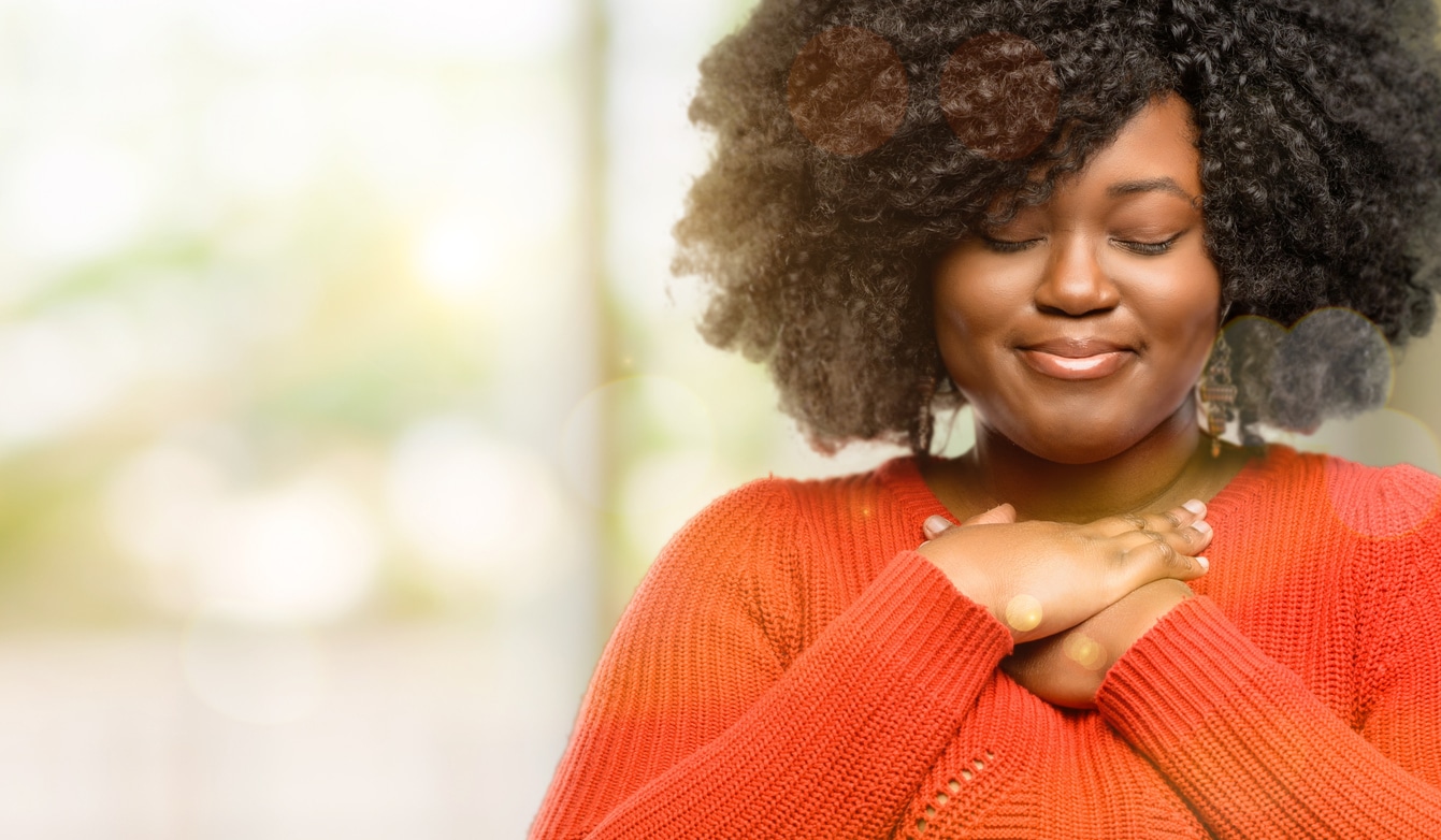 black woman with hands in heart, expressing love and health concept, outdoor
