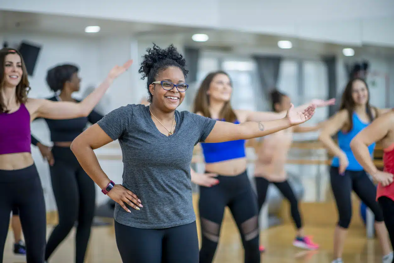 A diverse group dance along to the music together in an exercise dance class.