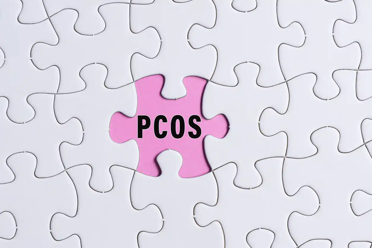 PCOS text on white jigsaw puzzle over pink background. Polycystic Ovary Syndrome Health Care concept.