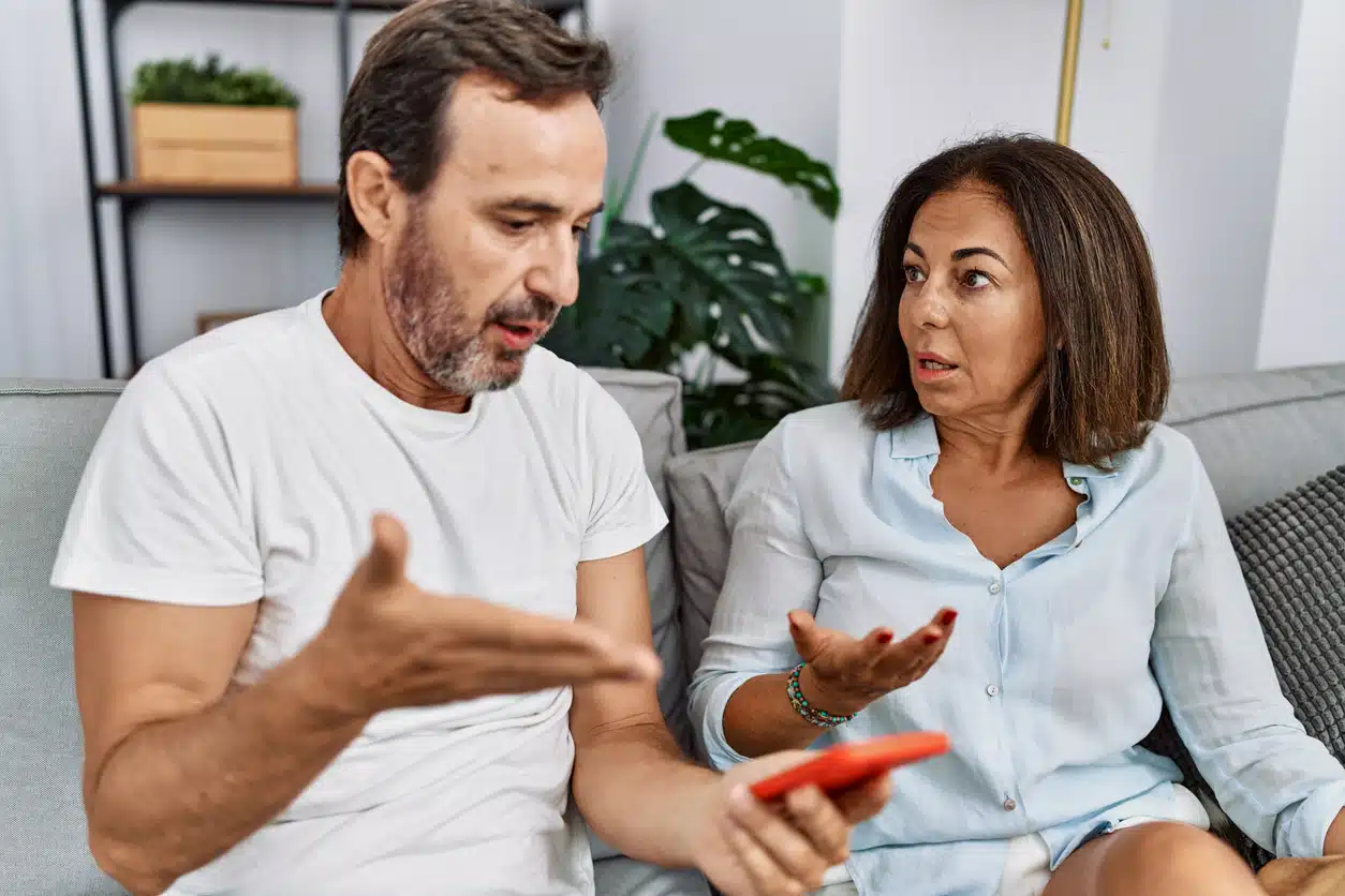 Middle age man and woman couple with problem for infidelity using smartphone at home