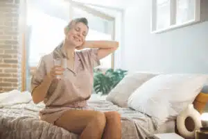 Mature woman waking up in sunny bedroom
