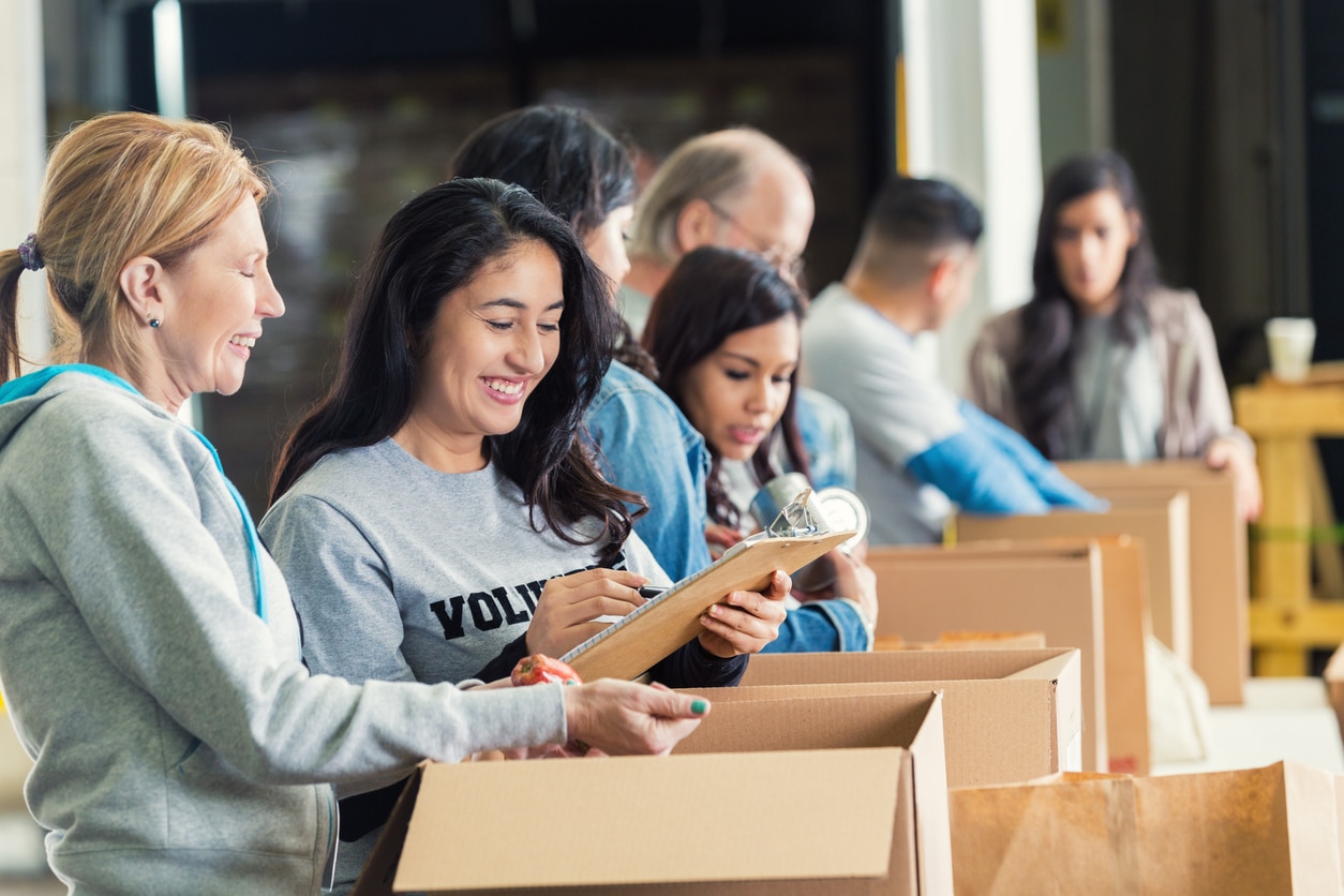 Diverse adults packing donation boxes in charity food bank