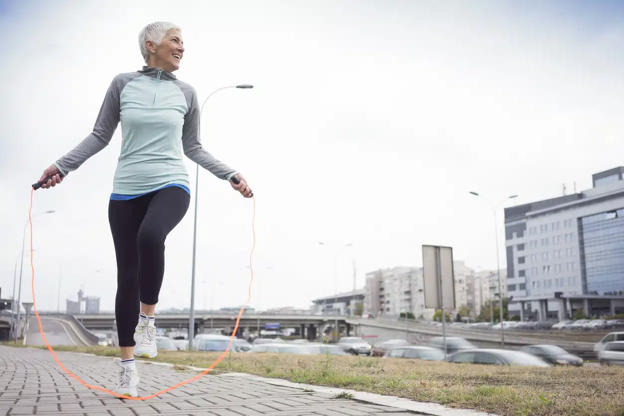 mature woman jumping rope in city
