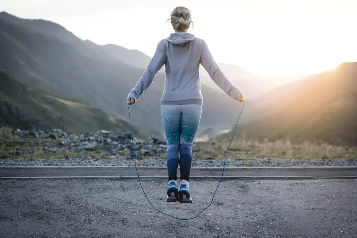 Adult woman exercising outdoors early in the morning. Jumping up