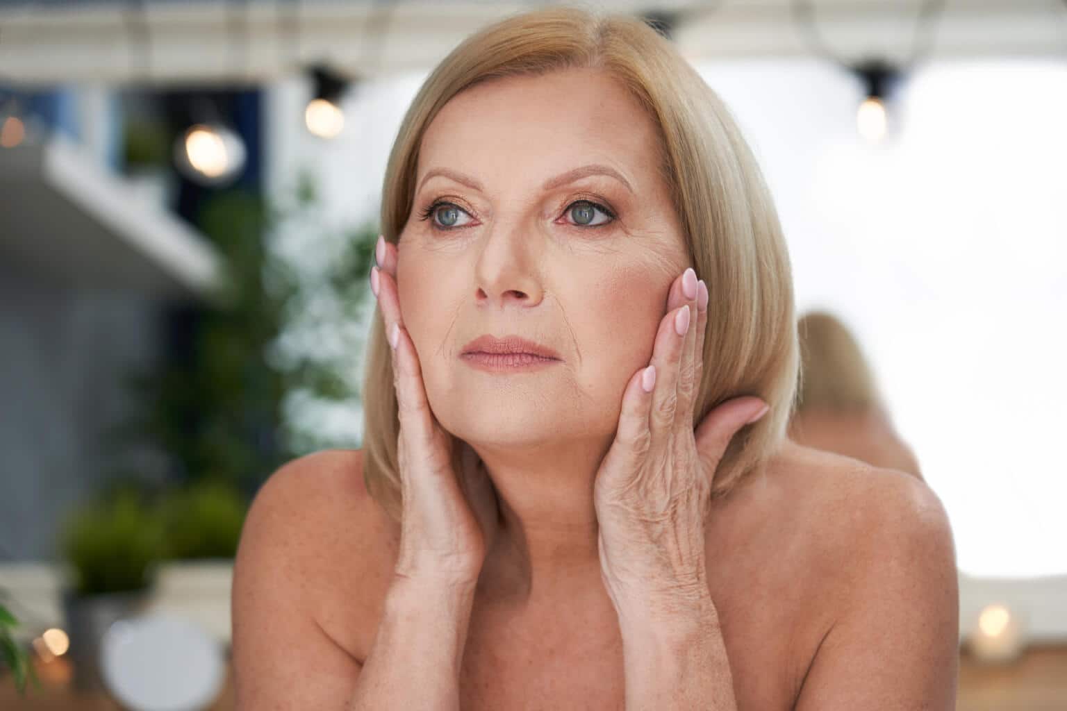 Best primer for Wrinkles; woman looking in the mirror at her face
