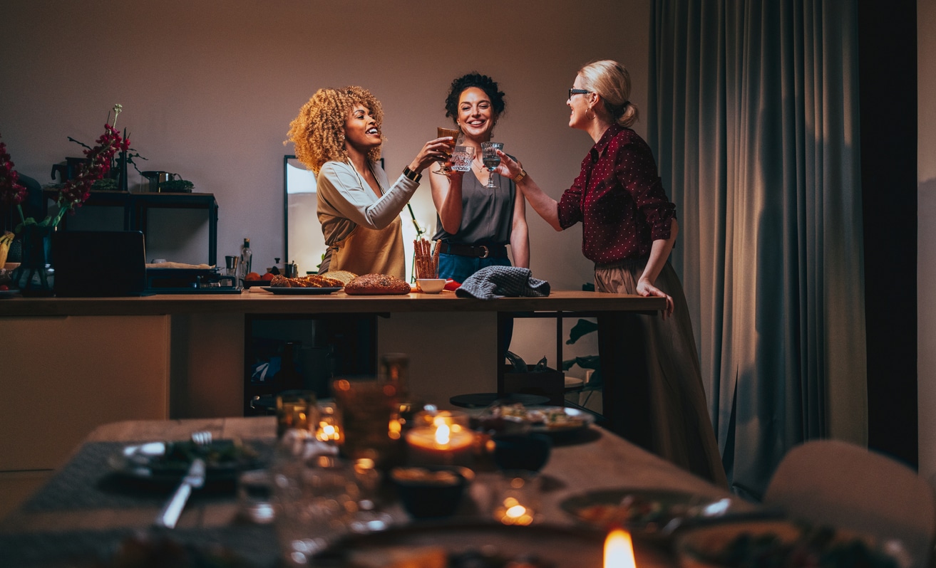 Three Woman Toasting With A Glass Of Wine During A Dinner Preparation
