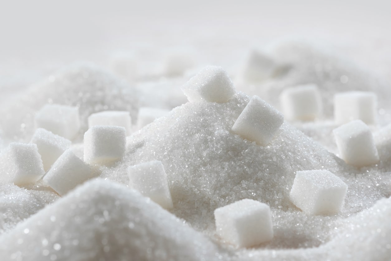 White granulated sugar and refined sugar cubes close-up in the kitchen.