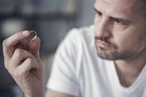 Disappointed man holding wedding ring after divorce case