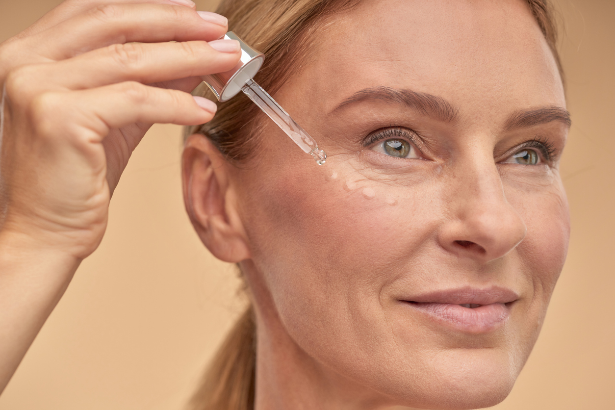 Woman applying serum to her face, anti-aging, skincare