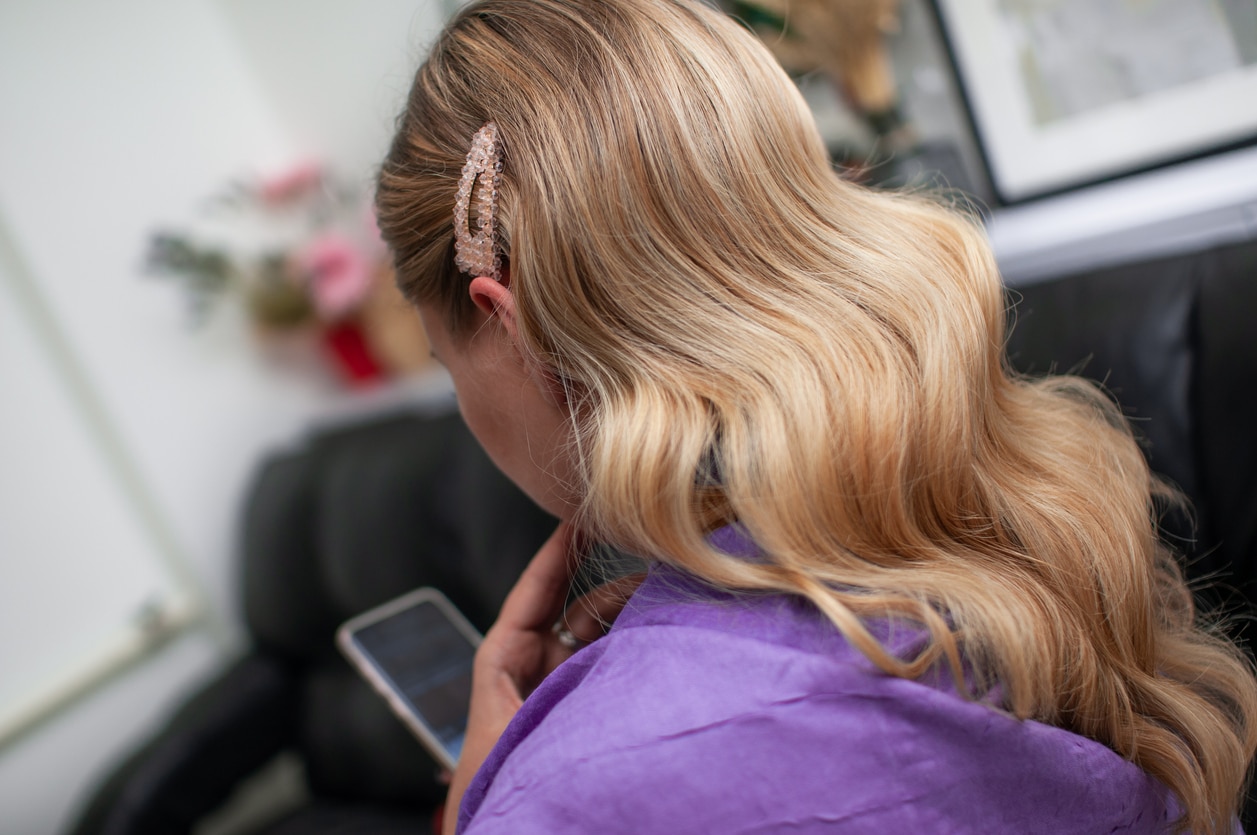 Blond woman with long hair and retro style hairstyle with a phone in her hand