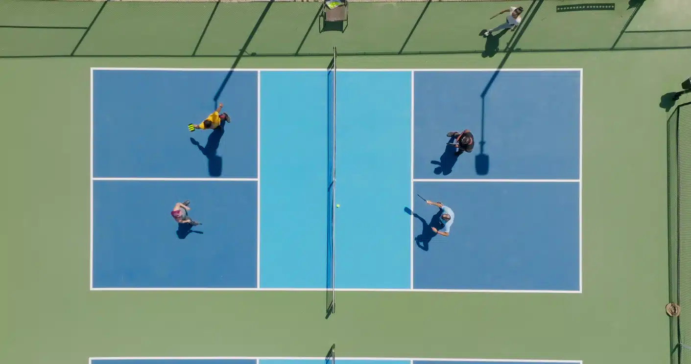 Top down drone shot of a group of people playing a doubles game of pickleball.