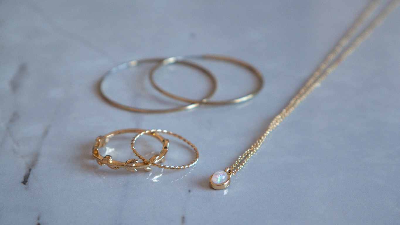 Gold jewelry on marble; necklace, rings and earrings