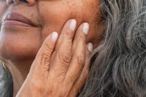 A wrinkled hand on a woman's face