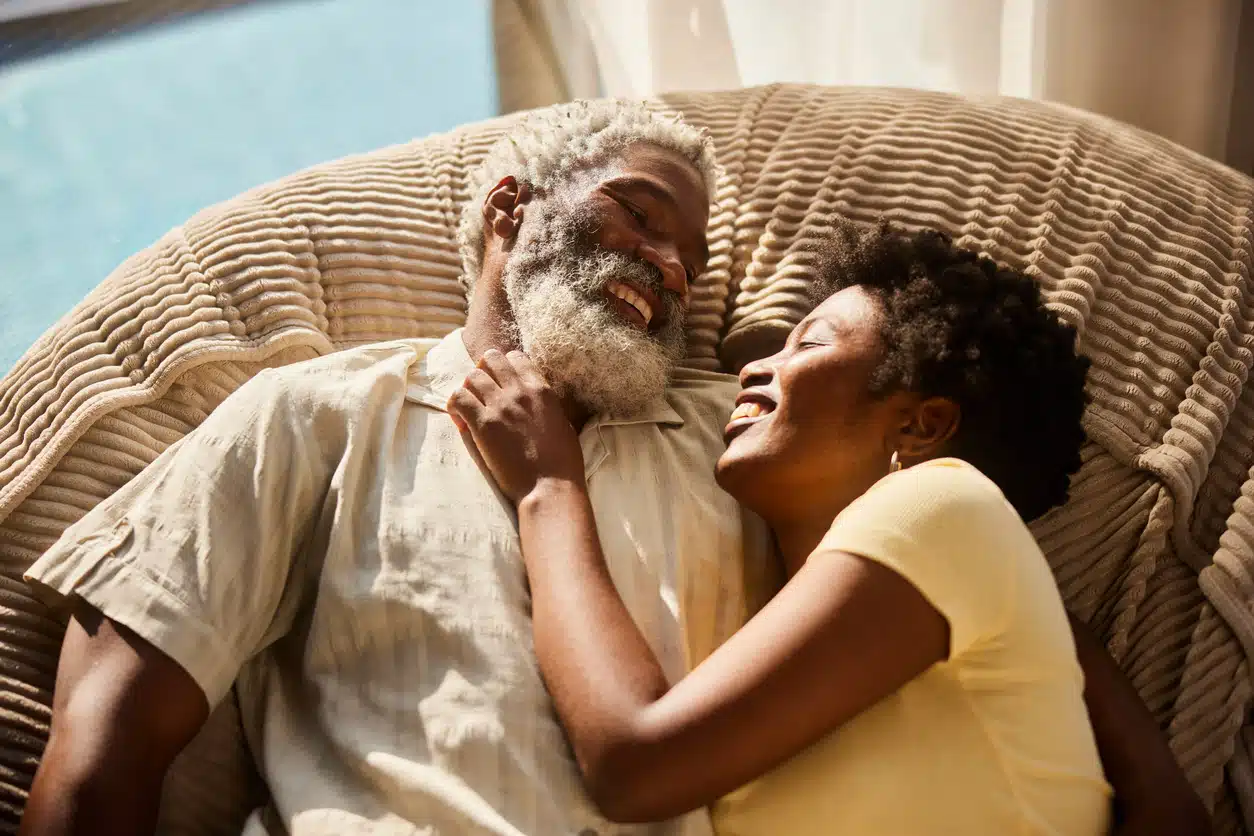 Affectionate couple lying face to face on a large bean bag chair and smiling while relaxing at home together