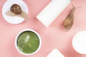 cosmetics with snail mucin on pink background, beauty skin care.