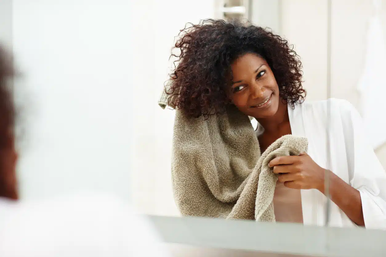Beautiful african woman drying her hair with a towel in the mirror