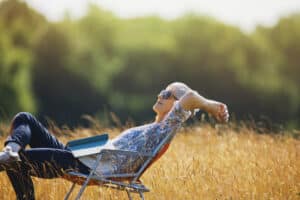Carefree senior woman relaxing with book in sunny field