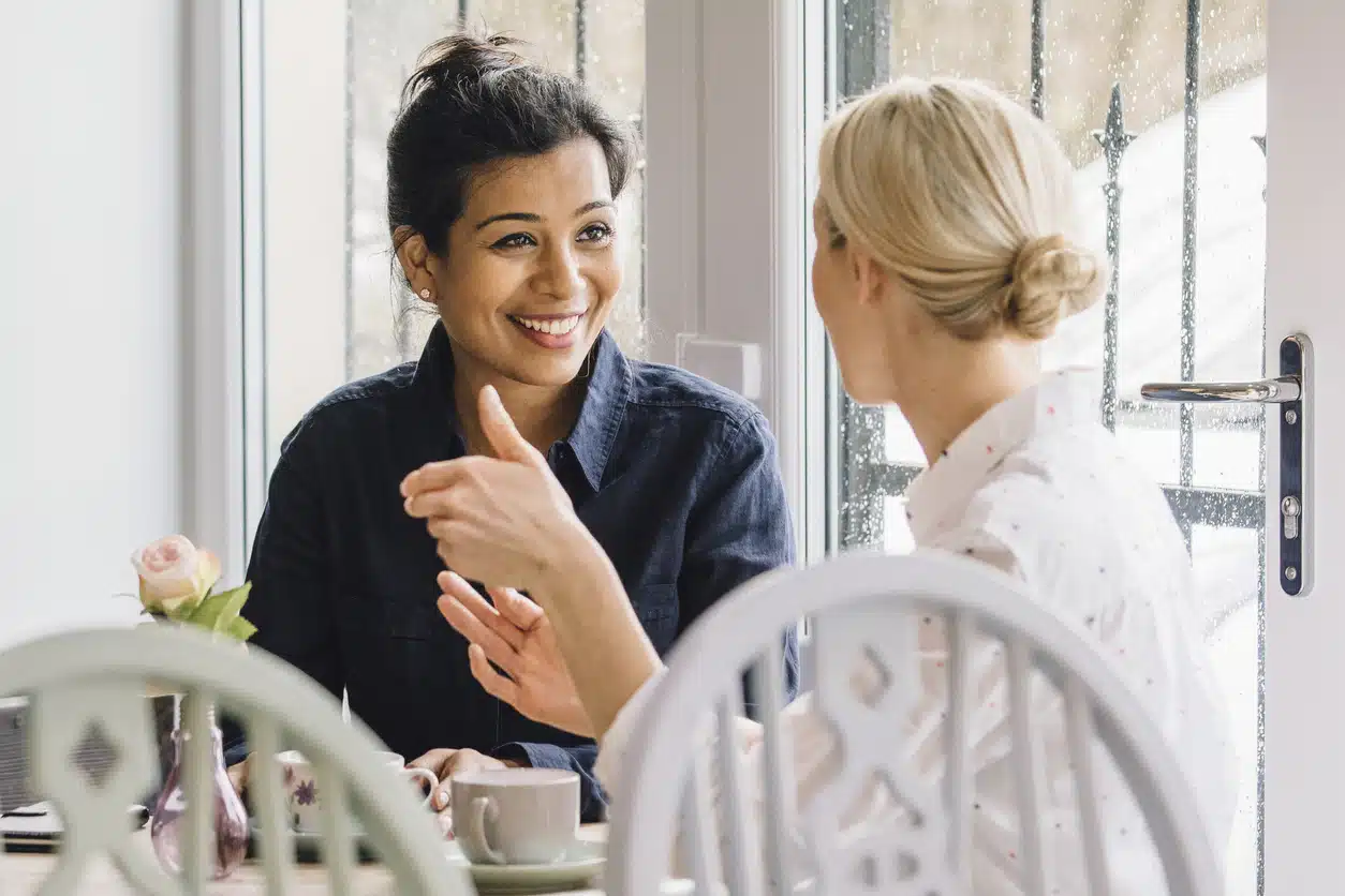 Women are sitting at a table in a cafe, socialising over tea.