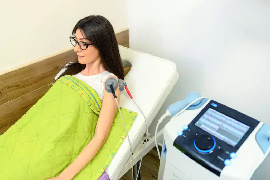 Electrical stimulation in physical therapy. Electrodes positioned at a patient's shoulder