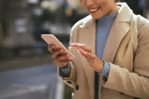 An anonymous Asian businesswoman typing text message while standing on the city street.