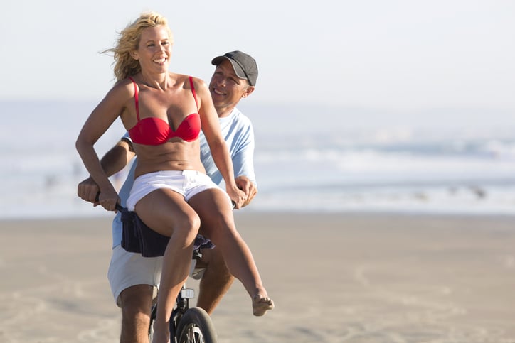 Couple riding a bike at the beach