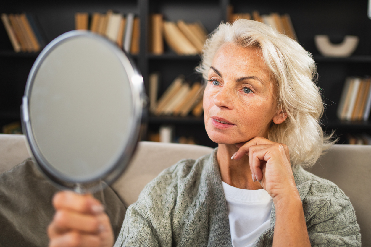 Psychodermatology: The Mental Connection To Physical Appearance; woman looking in the mirror