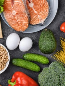 A set of products for a flexible diet. Salmon steak, chicken, chickpeas, mung beans and vegetables on a black background.