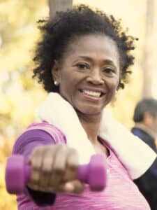 Exercises to burn upper body fat; woman lifting dumbbells; exercising outside