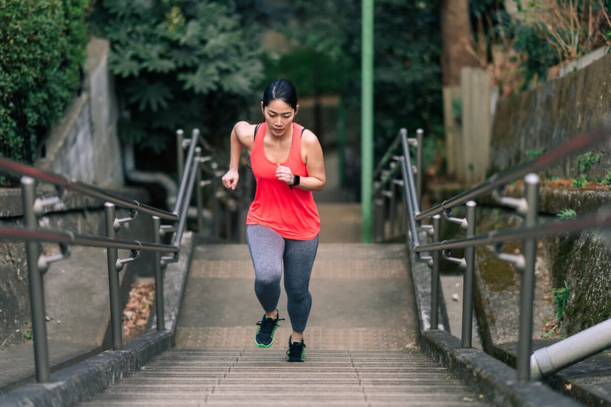 A young female athlete is running up stairs.