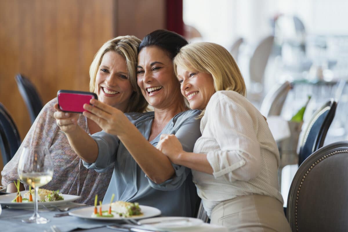 Three mature women taking selfie in restaurant