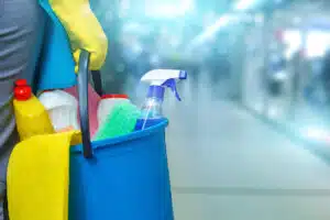 Cleaning lady with a bucket and cleaning products on blurred background .