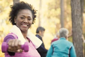 Exercises to burn upper body fat; woman lifting dumbbells; exercising outside